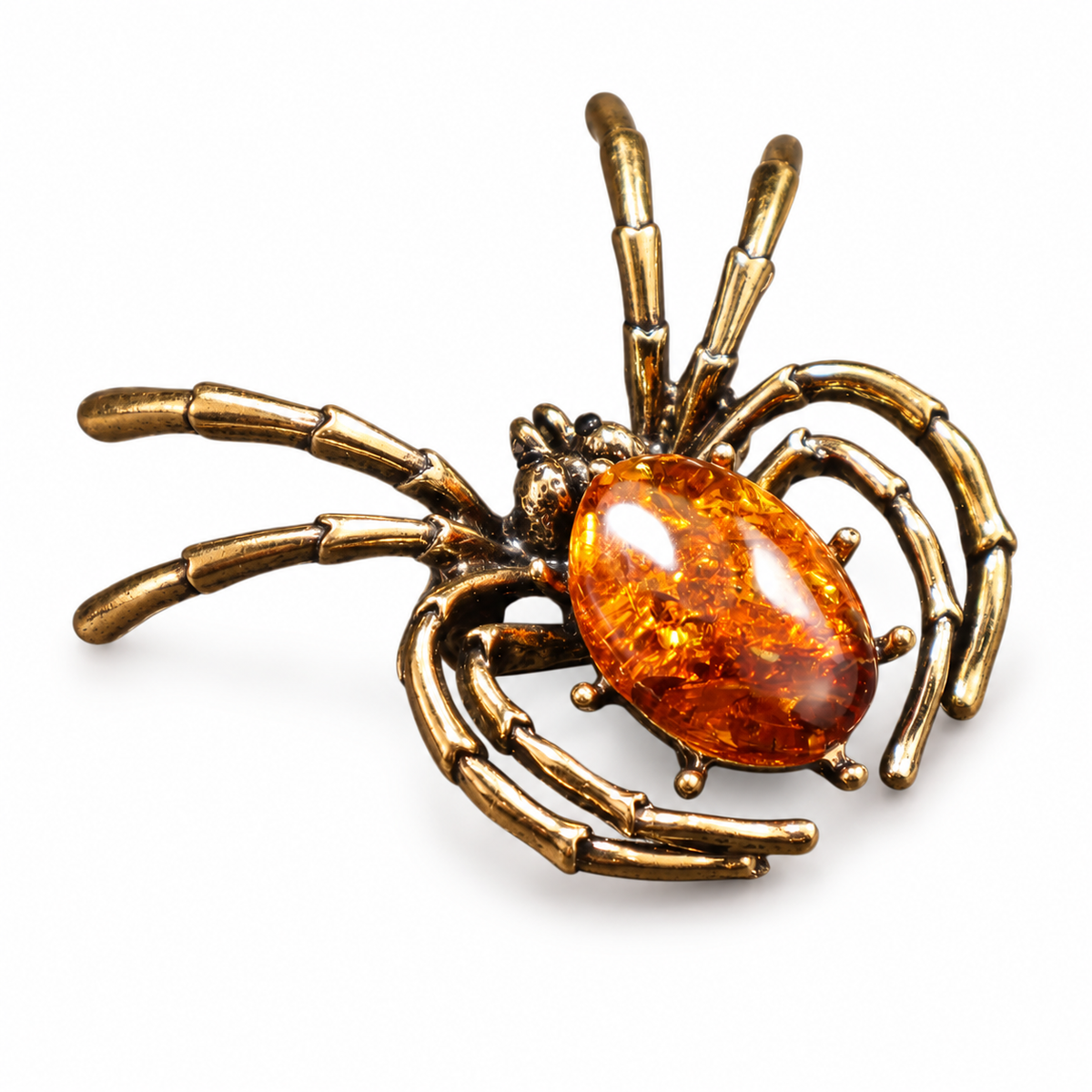 KIZIMA antique-gold-tone spider brooch with oval cognac Baltic amber on white studio background.