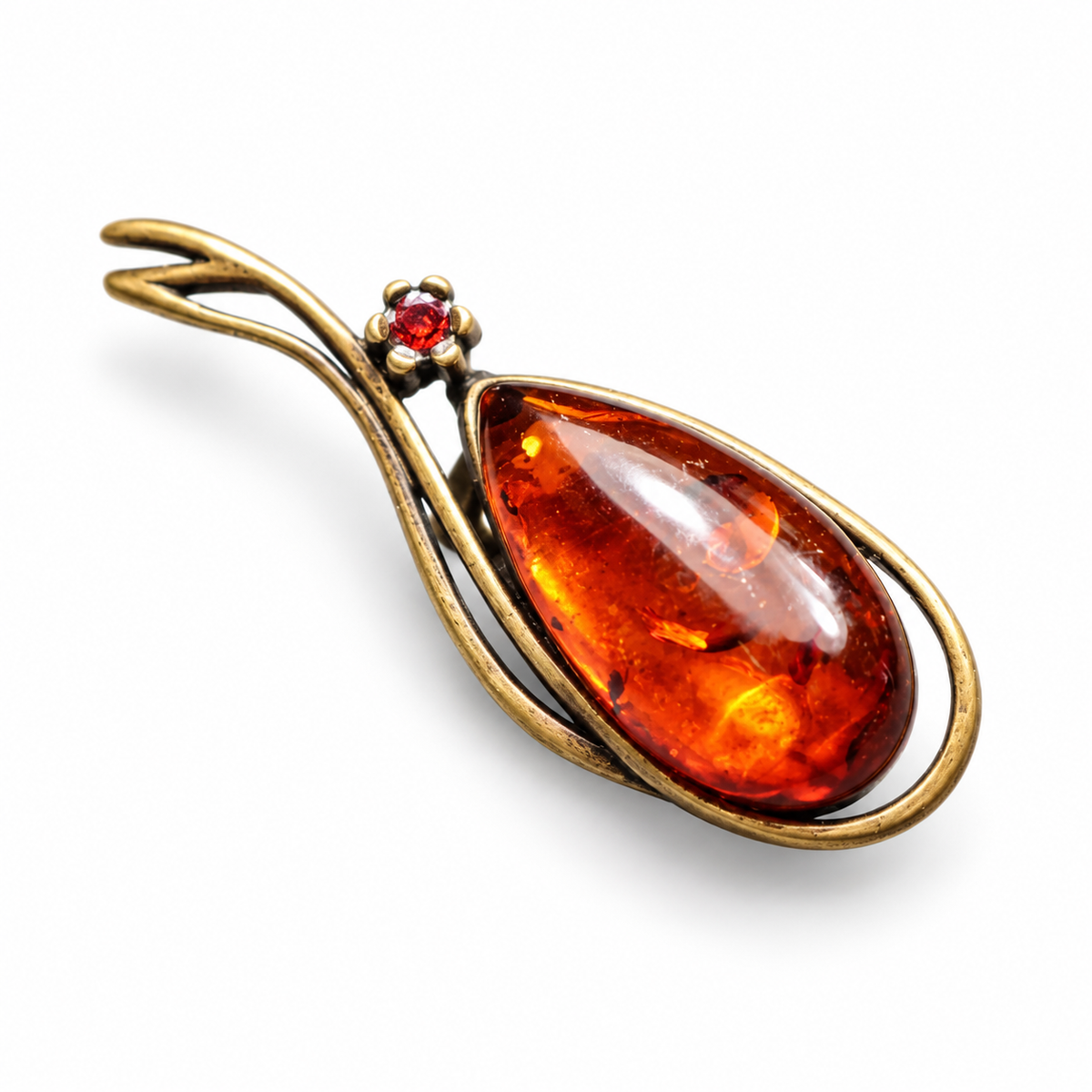 KIZIMA antique bronze-tone teardrop brooch with reddish cognac Baltic amber and a small red accent stone on a white studio background.