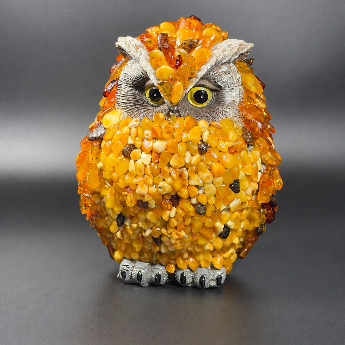 Enhanced original front photograph of KIZIMA VIP Baltic amber owl 5598752O, with yellow eyes, gray face and natural amber mosaic.