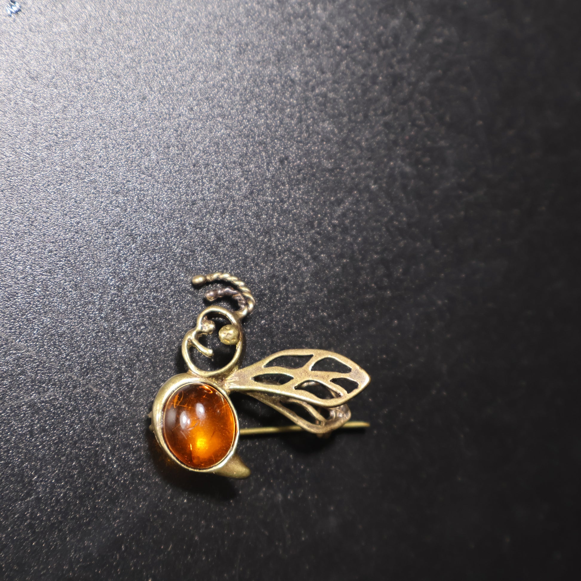 Handmade Baltic amber bee brooch close-up showing natural stone