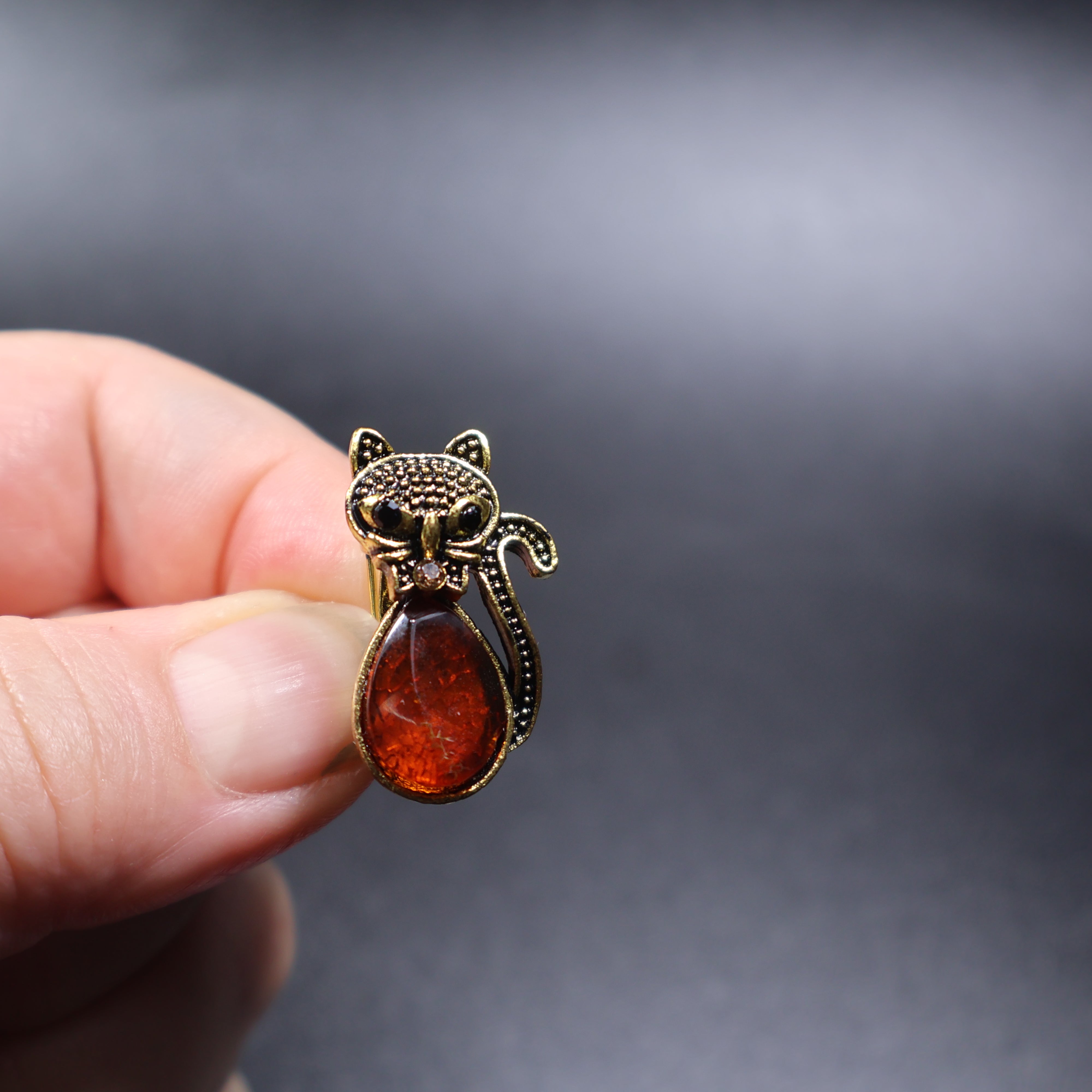 Handmade Baltic amber black cat brooch gold close-up showing natural stone