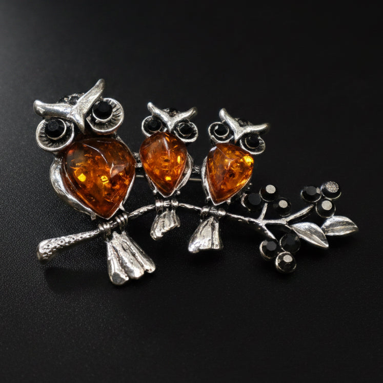Handmade Baltic amber three owls on a branch brooch close-up