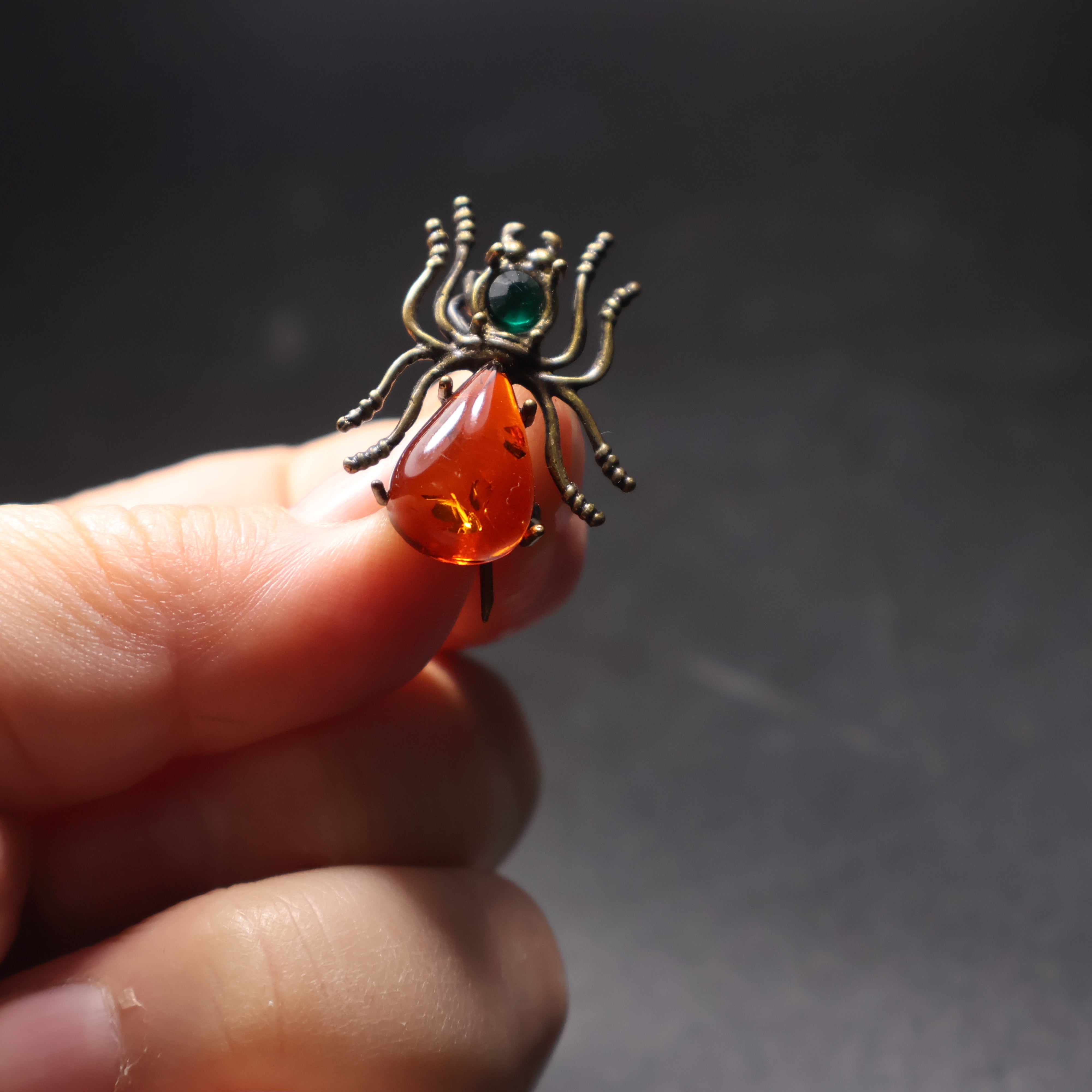 Handmade Baltic amber spider brooch close-up showing natural stone belly