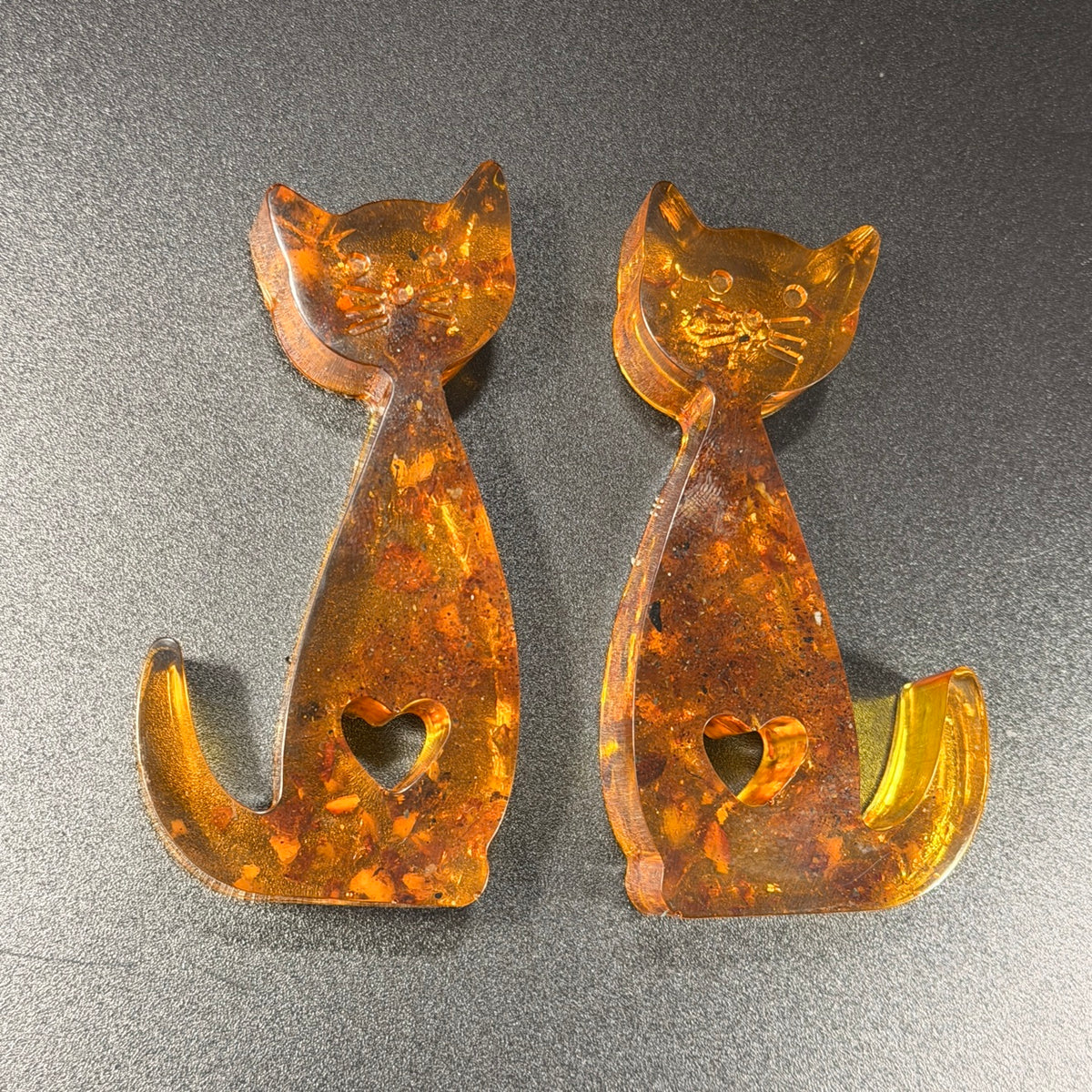 Top view of two honey and cognac Baltic amber cats with heart-shaped cutouts, KIZIMA gift for cat lover