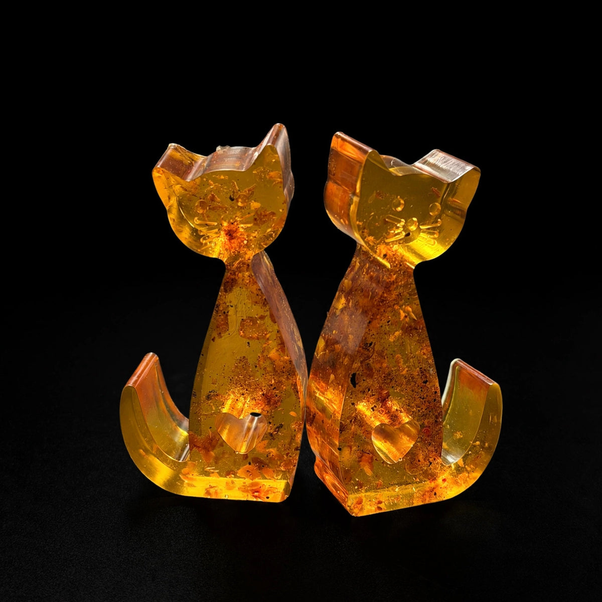 Made in USA natural Baltic amber cat figurines set of 2 — studio shot on black background, honey amber cats with heart cutout by KIZIMA