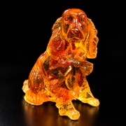 Made in USA natural Baltic amber Cocker Spaniel figurine, sitting spaniel with long wavy ears and bow glowing honey-cognac on black studio background — KIZIMA® Brooklyn NY