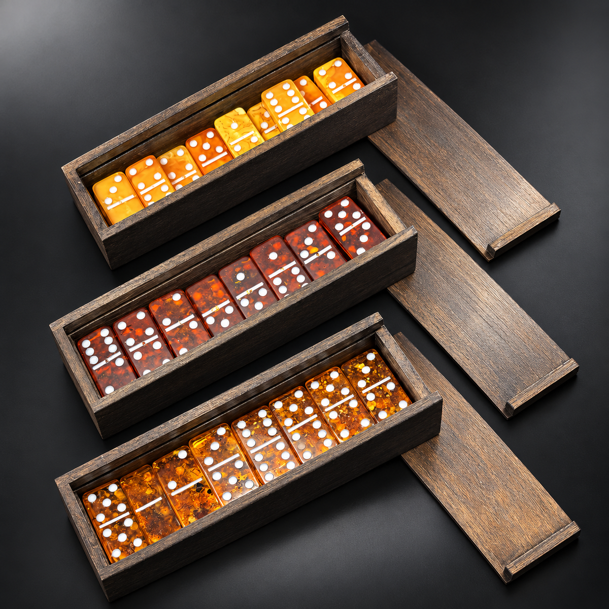 Three Natural Baltic Amber domino sets by KIZIMA® side by side — golden, cherry and cognac amber tiles in engraved wooden boxes, color comparison, Made in USA