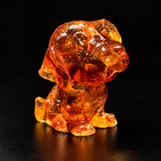 Made in USA natural Baltic amber Labrador puppy figurine, sitting puppy with floppy ears and tilted head glowing honey-cognac on black studio background — KIZIMA® Brooklyn NY