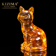 Made in USA natural Baltic amber sitting cat figurine by KIZIMA®, cognac amber with golden inclusions on black studio background