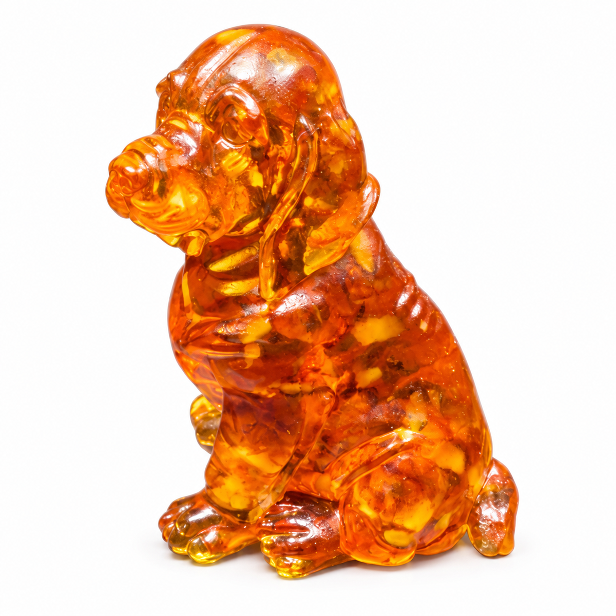 Amber spaniel figurine on white, showing long rounded ears, smooth haunches and honey-colored patches through its glossy body.