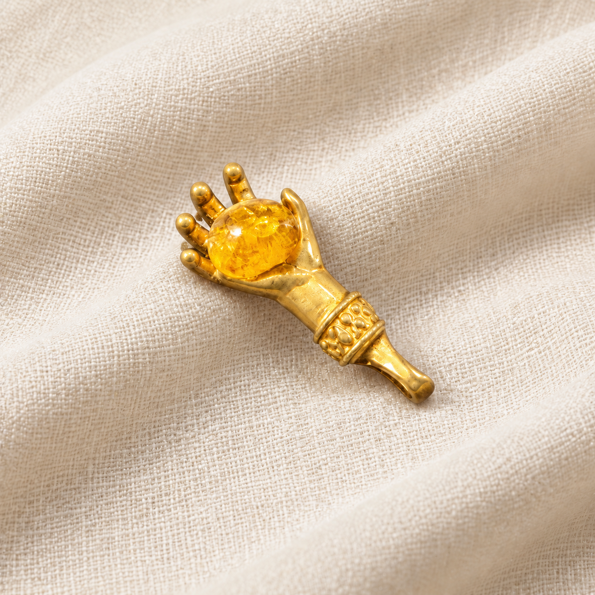 Made in USA Natural Baltic Amber money hand amulet by KIZIMA® resting diagonally on light fabric