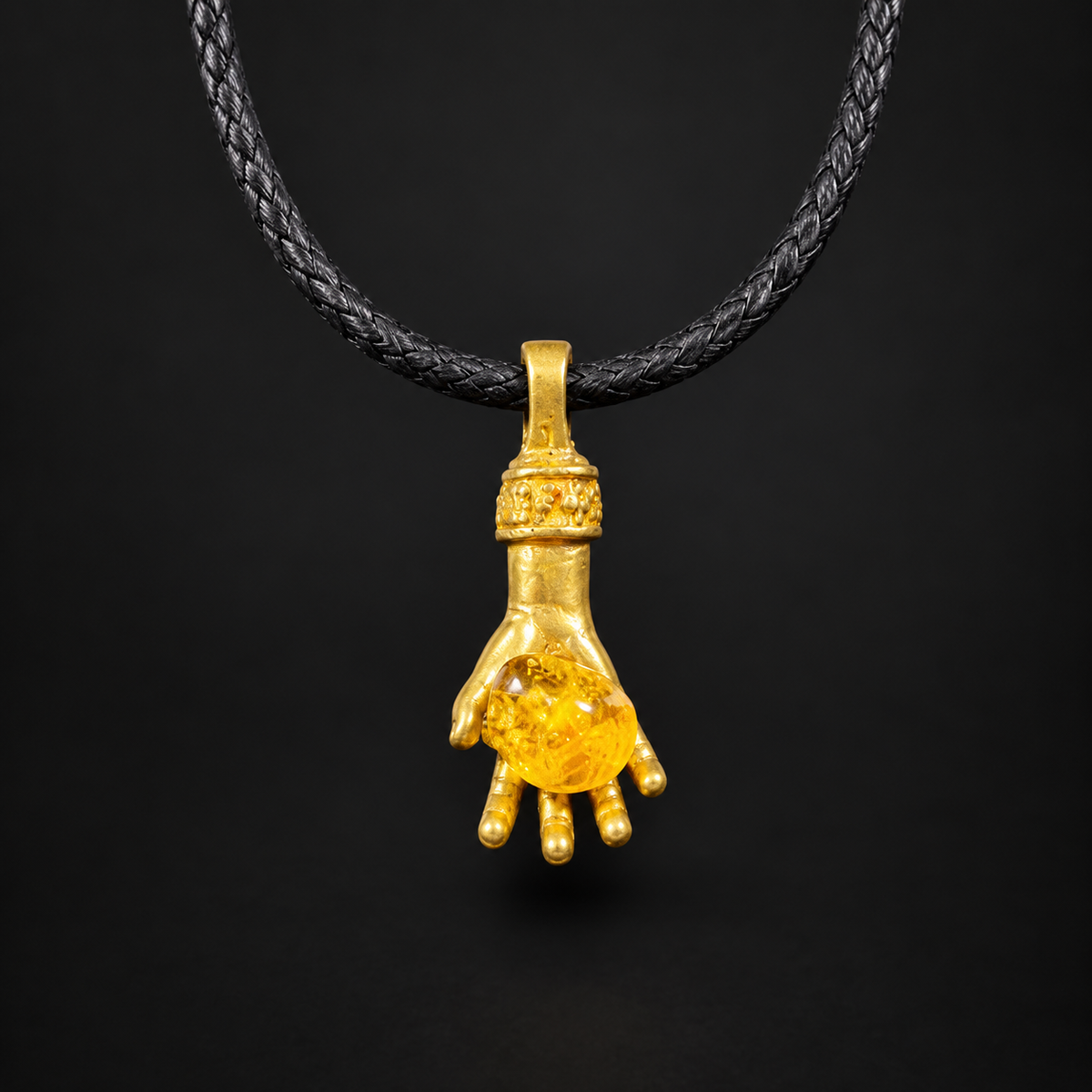 Made in USA Natural Baltic Amber money hand pendant on a dark cord by KIZIMA®, gold-tone metal hand holding amber, black studio background