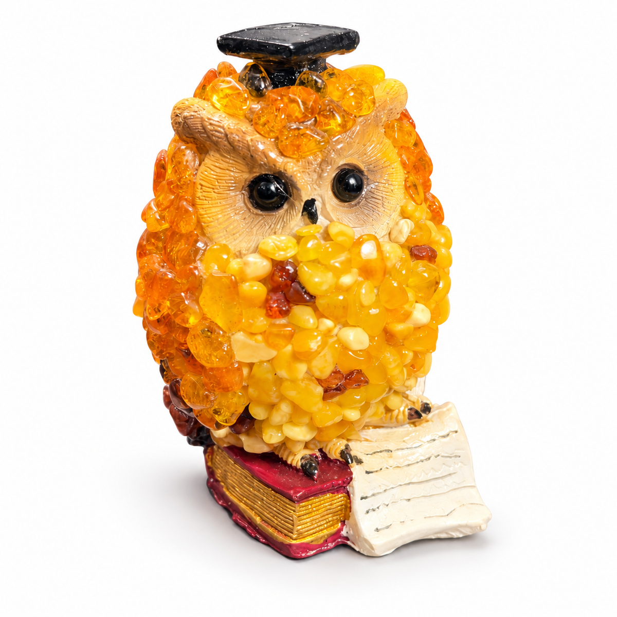 Golden yellow owl figurine with book and scroll on a white studio background